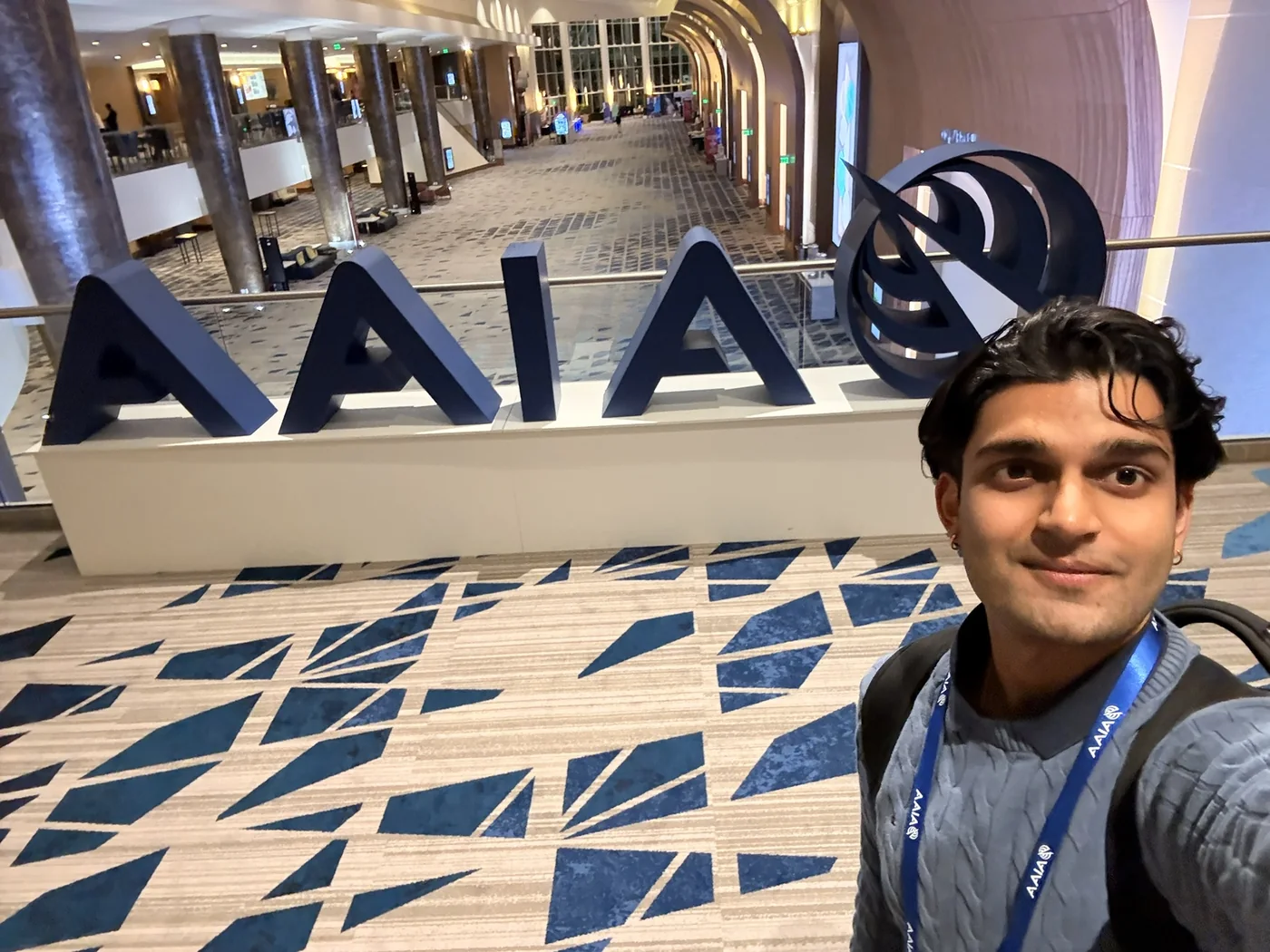 Haitish beside an AIAA display at a conference